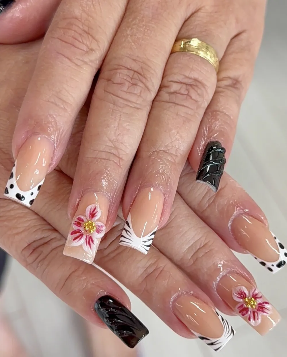 French tip nails with cow and zebra prints, black accents and pink 3D flowers