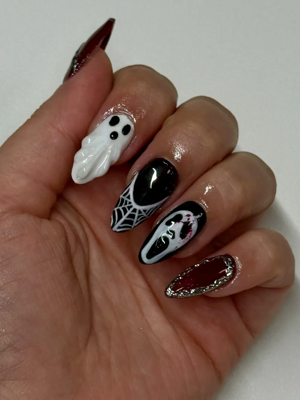 Almond nails with a 3D ghost, spider web, ghost face and chrome burgundy design